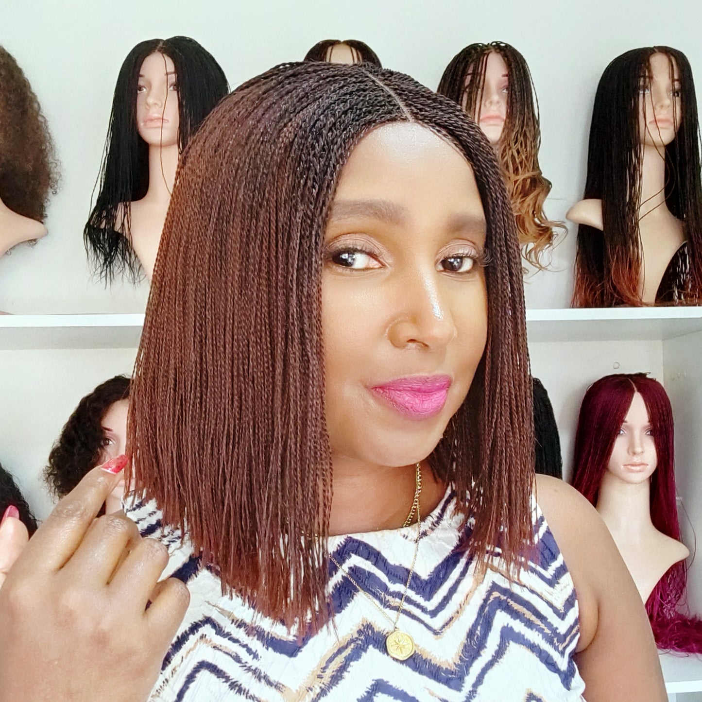 Woman with braided hair in front of a display of wigs.