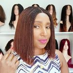 Load image into Gallery viewer, Woman with braided hair in front of a display of wigs.
